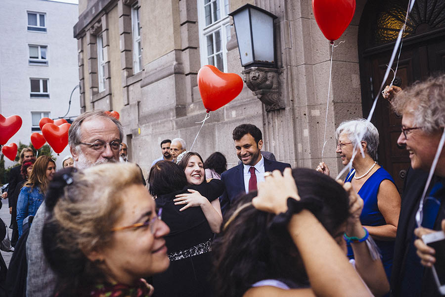 Berlin city wedding - Bride and groom congratulated by family holding hed balloons